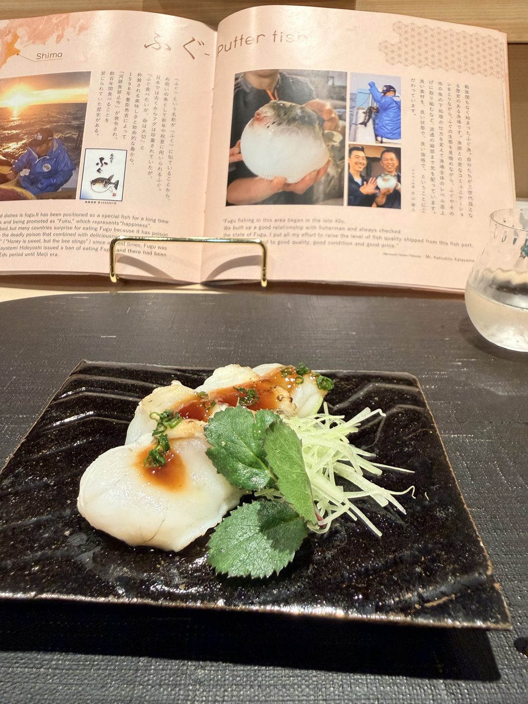 Fugu with ponzu, shiso and shredded daikon on a black plate