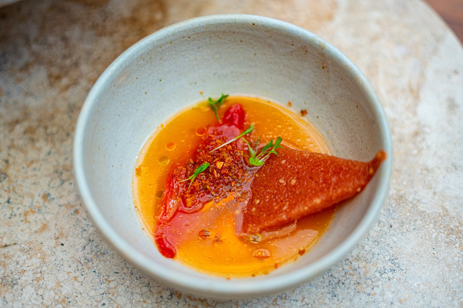 A broth course served at a candlelit table