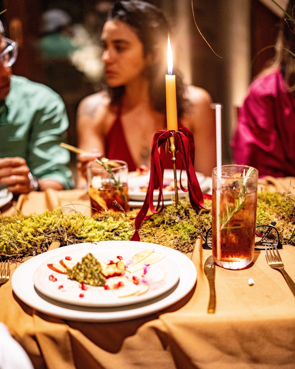 A plated course on a candlelit table with a moss runner