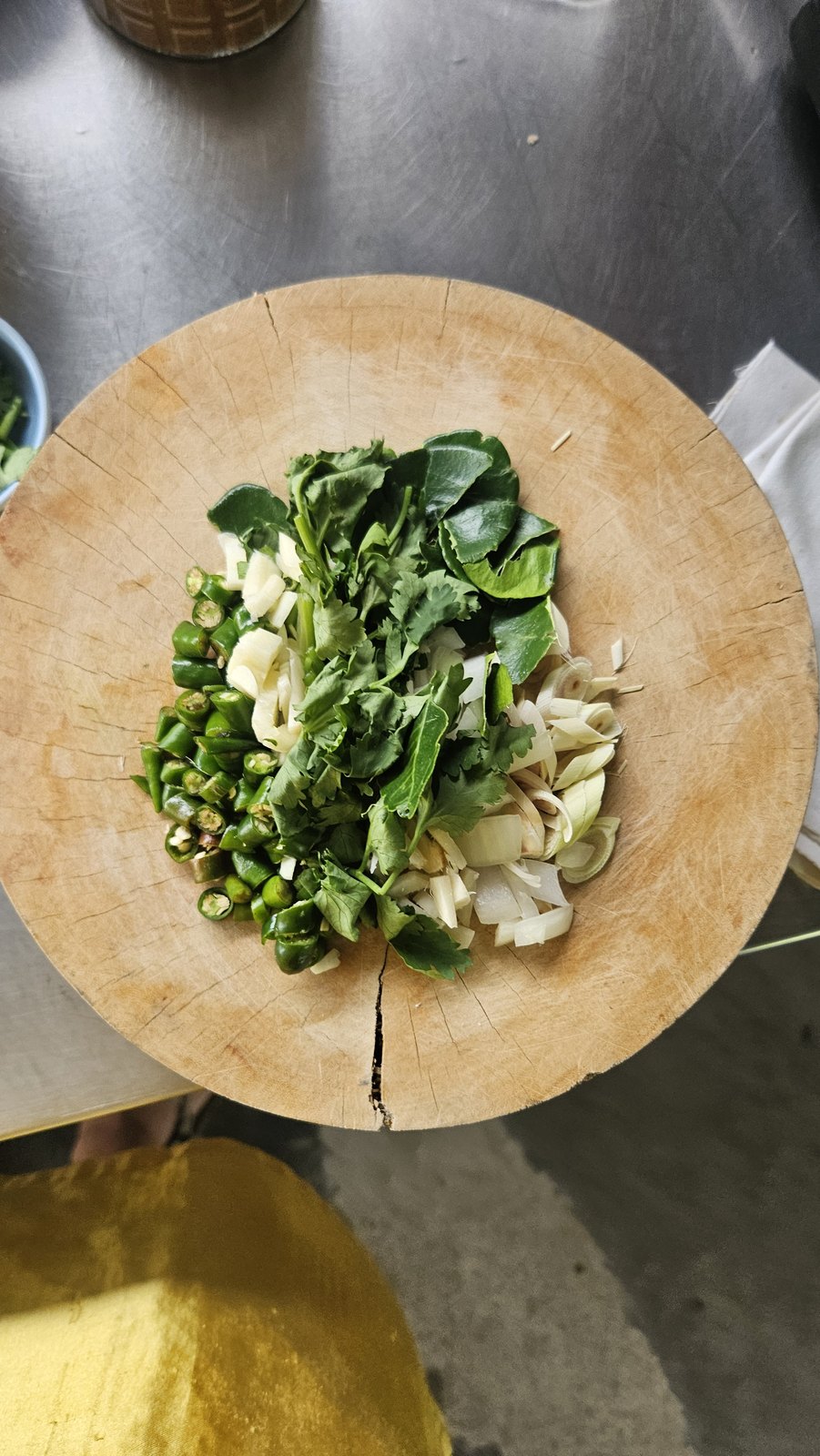 Greens and herbs on the chopping board, the stone mortar behind