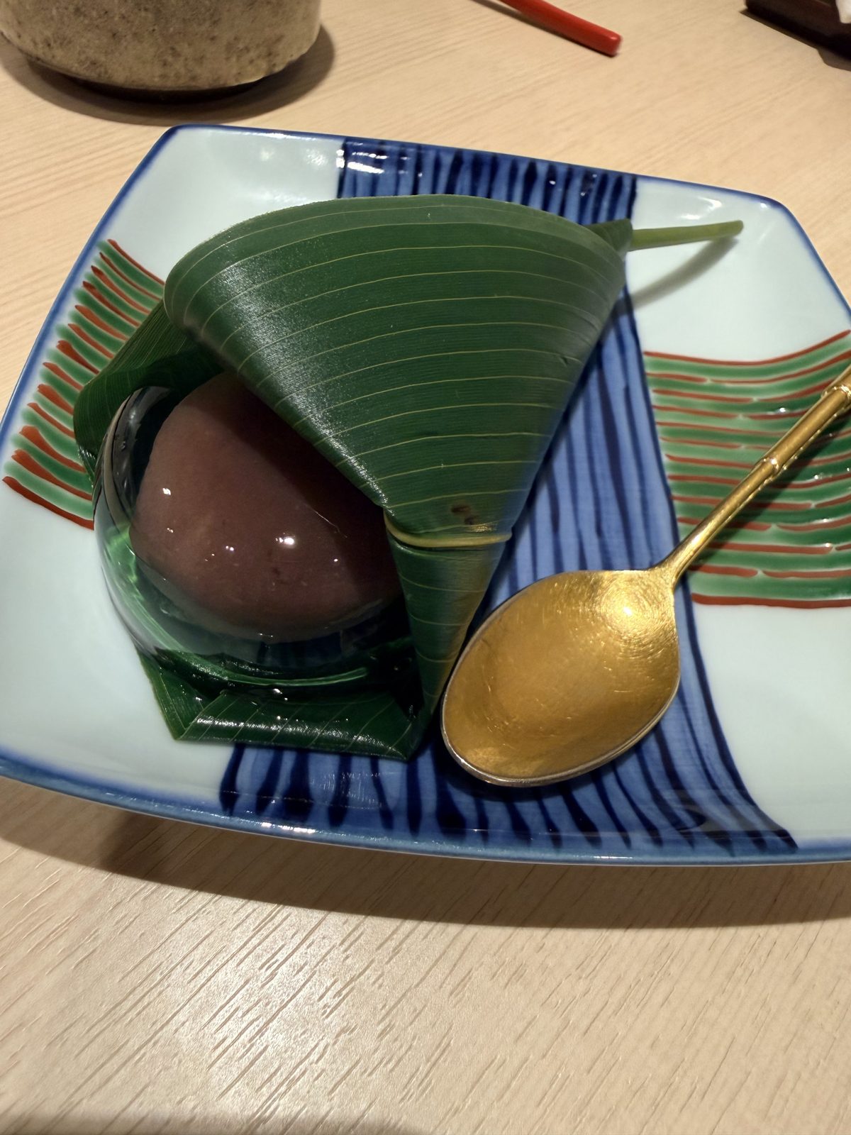 Mizu-manju wrapped in bamboo leaf with a gilded spoon