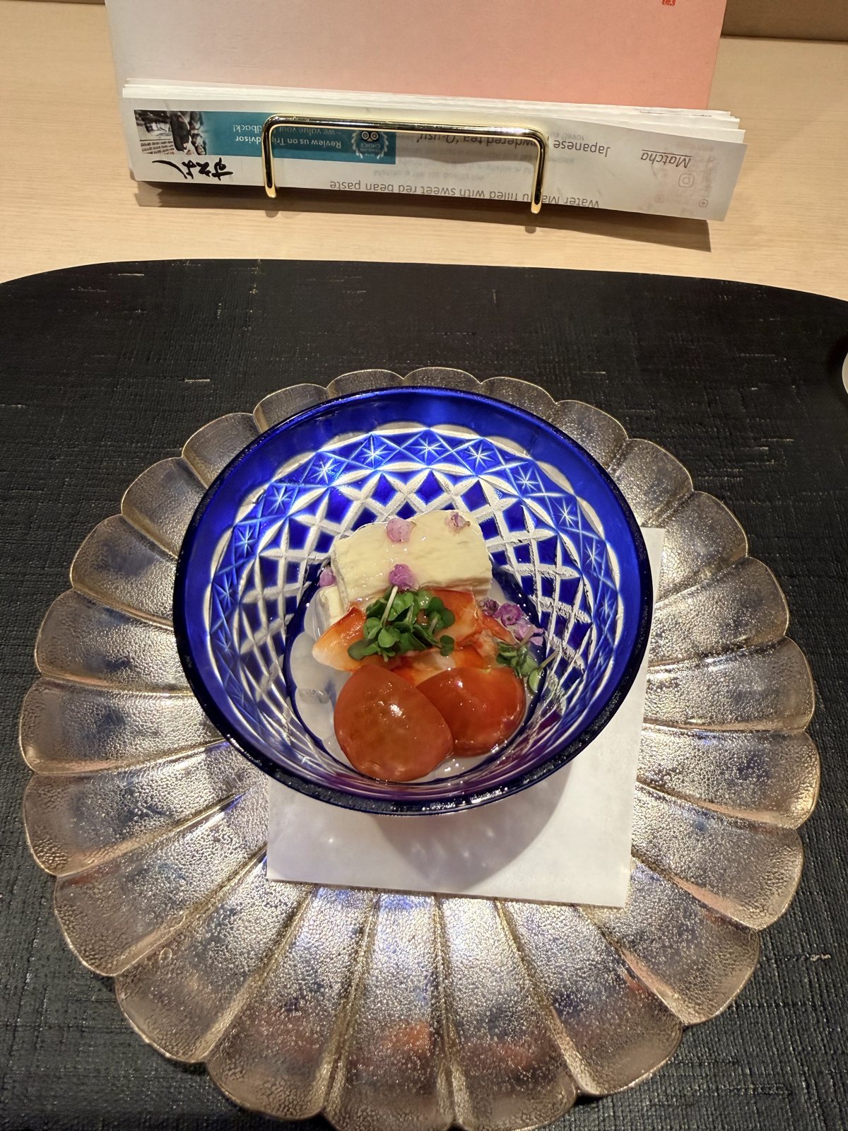 Tomato and tofu course in a blue kiriko glass on a silver petal plate