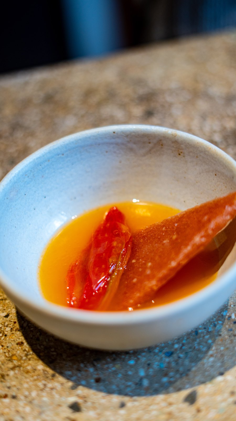The clear broth in the grey bowl
